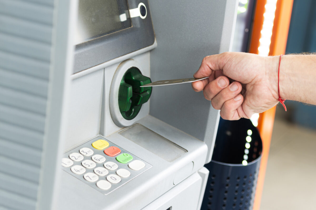 Human hand inserting a credit card into an ATM