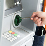 Human hand inserting a credit card into an ATM