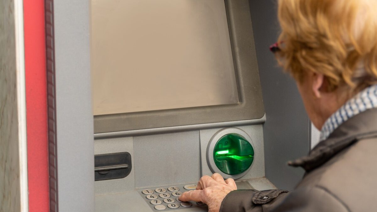 Close up, an elderly woman uses an ATM