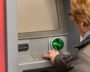 Close up, an elderly woman uses an ATM