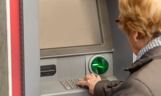 Close up, an elderly woman uses an ATM