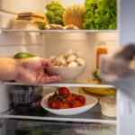 Man's hand taking out mushroom bowl from refrigerator at home.