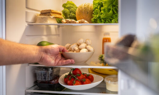 Man's hand taking out mushroom bowl from refrigerator at home.