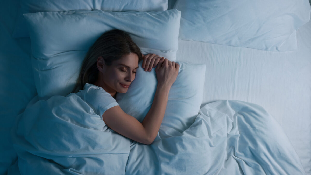 Woman sleeping in bed at night, above view. Space for text