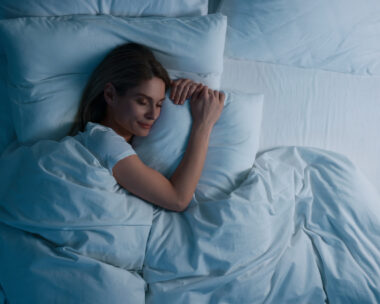 Woman sleeping in bed at night, above view. Space for text