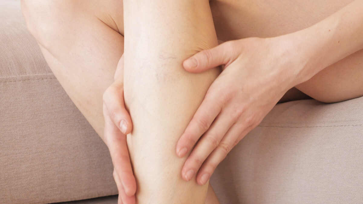 A young girl massages her thin and long tired legs at home after long working day. Prevention of varicose veins.