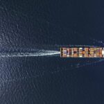 Aerial top view container ship in export and import business and logistics. Shipping cargo to harbor by crane.