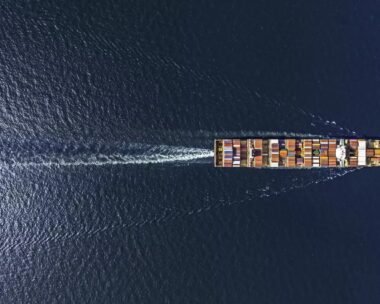 Aerial top view container ship in export and import business and logistics. Shipping cargo to harbor by crane.