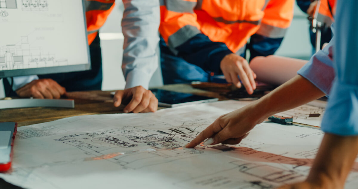 Closeup of team of industrial engineers meeting analyze machinery blueprints consult project