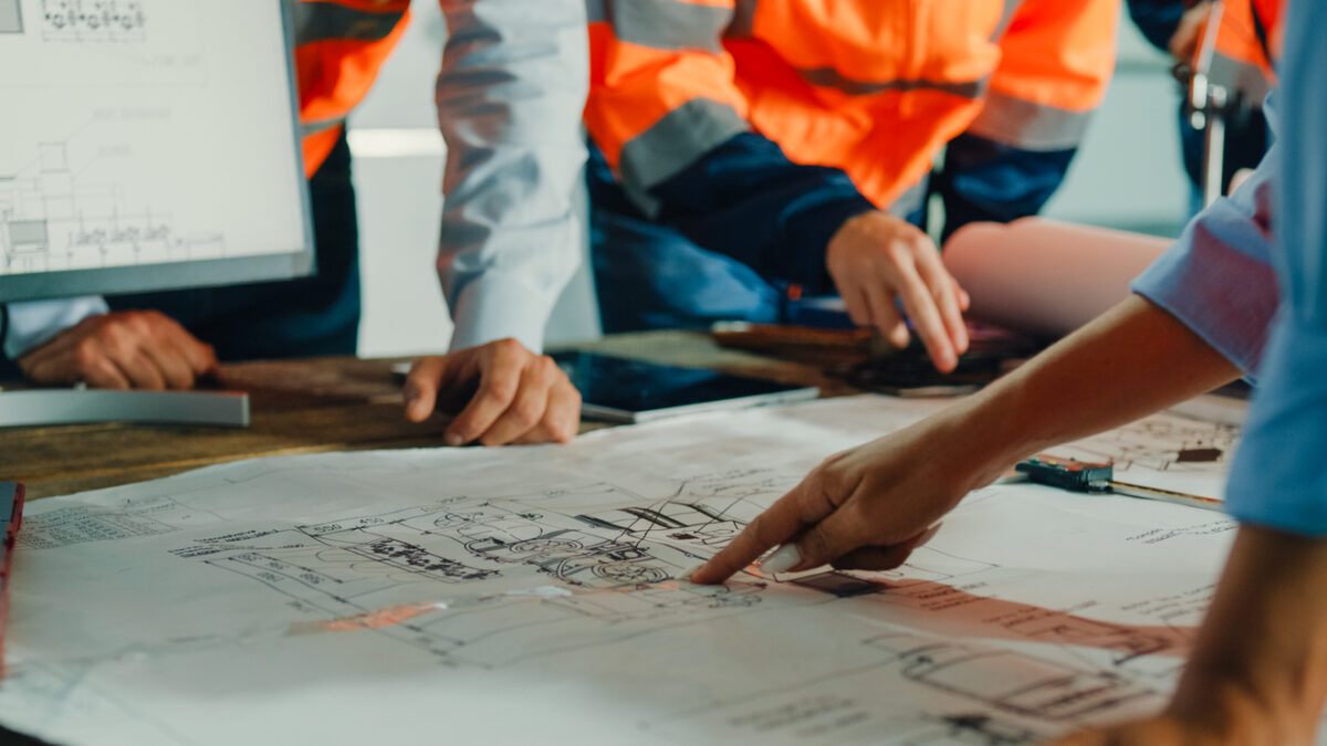 Closeup of team of industrial engineers meeting analyze machinery blueprints consult project