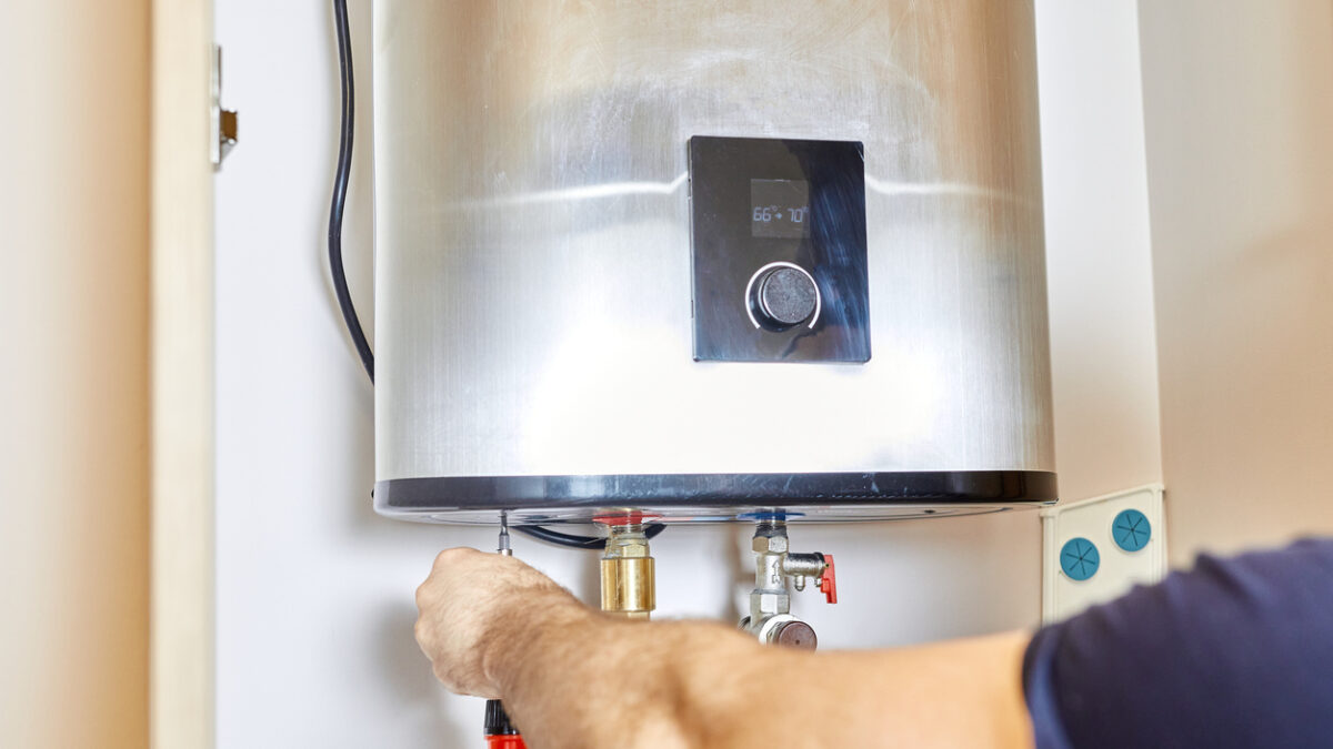 the man tightens the pipe nut in the water heating system