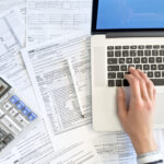 Doing taxes with laptop and tax forms in a house