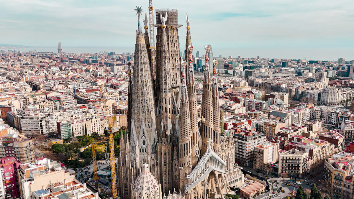 Aerial view of Sagrada Familia Cathedral in Barcelona, Catalonia, Spain, Aerial view of Barcelona Eixample residential area and Sagrada Familia Basilica, most famous travel destinations in europe The Basílica i Temple Expiatori de la Sagrada Família, otherwise known as Sagrada Família, is a church under construction in the Eixample district of Barcelona, Catalonia, Spain. It is the largest unfinished Catholic church in the world. Designed by Catalan architect Antoni Gaudí (1852–1926), his work on Sagrada Família is part of a UNESCO World Heritage Site. On 7 November 2010, Pope Benedict XVI consecrated the church and proclaimed it a minor basilica. On 19 March 1882, construction of the Sagrada Família began under architect Francisco de Paula del Villar. In 1883, when Villar resigned, Gaudí took over as chief architect, transforming the project with his architectural and engineering style, combining Gothic and curvilinear Art Nouveau forms. Gaudí devoted the remainder of his life to the project, and he is buried in the church's crypt. At the time of his death in 1926, less than a quarter of the project was complete.