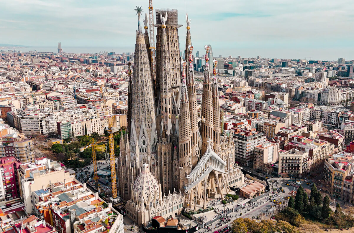 Aerial view of Sagrada Familia Cathedral in Barcelona, Catalonia, Spain, Aerial view of Barcelona Eixample residential area and Sagrada Familia Basilica, most famous travel destinations in europe The Basílica i Temple Expiatori de la Sagrada Família, otherwise known as Sagrada Família, is a church under construction in the Eixample district of Barcelona, Catalonia, Spain. It is the largest unfinished Catholic church in the world. Designed by Catalan architect Antoni Gaudí (1852–1926), his work on Sagrada Família is part of a UNESCO World Heritage Site. On 7 November 2010, Pope Benedict XVI consecrated the church and proclaimed it a minor basilica. On 19 March 1882, construction of the Sagrada Família began under architect Francisco de Paula del Villar. In 1883, when Villar resigned, Gaudí took over as chief architect, transforming the project with his architectural and engineering style, combining Gothic and curvilinear Art Nouveau forms. Gaudí devoted the remainder of his life to the project, and he is buried in the church's crypt. At the time of his death in 1926, less than a quarter of the project was complete.