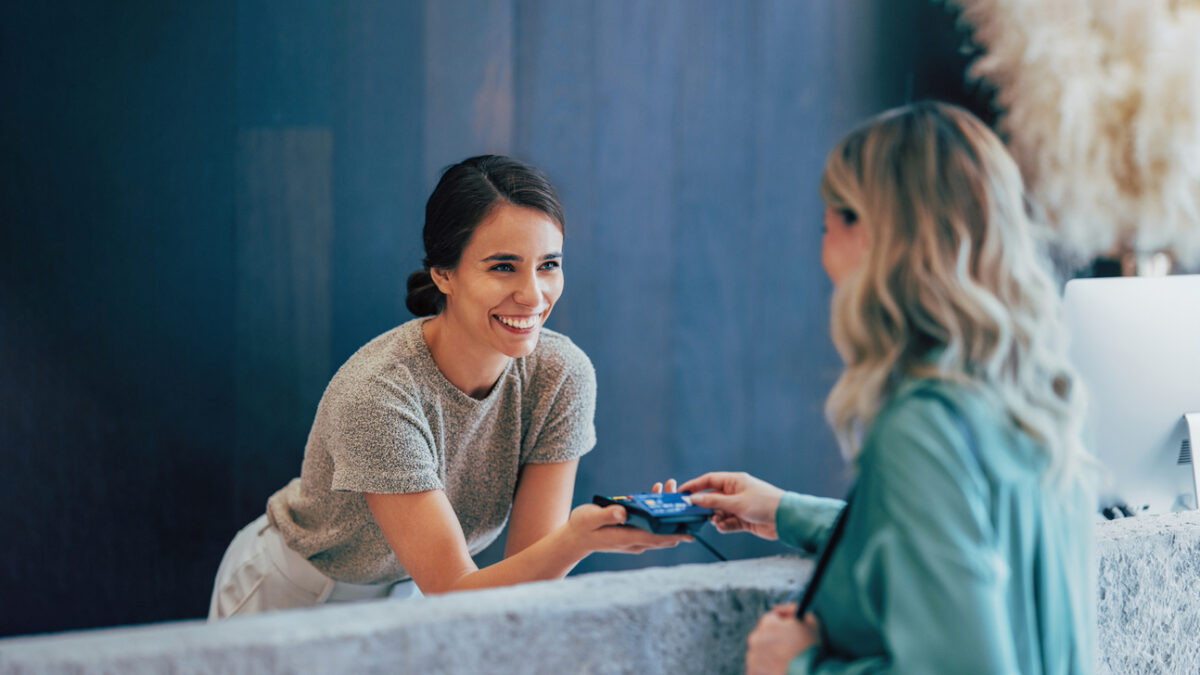 Two professional women engage in a pleasant business exchange at a stylish office. One hands a business card to another, highlighting teamwork and communication.