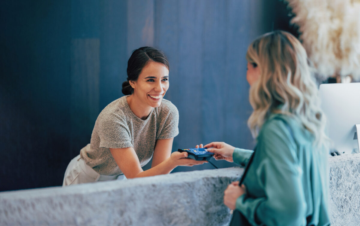 Two professional women engage in a pleasant business exchange at a stylish office. One hands a business card to another, highlighting teamwork and communication.