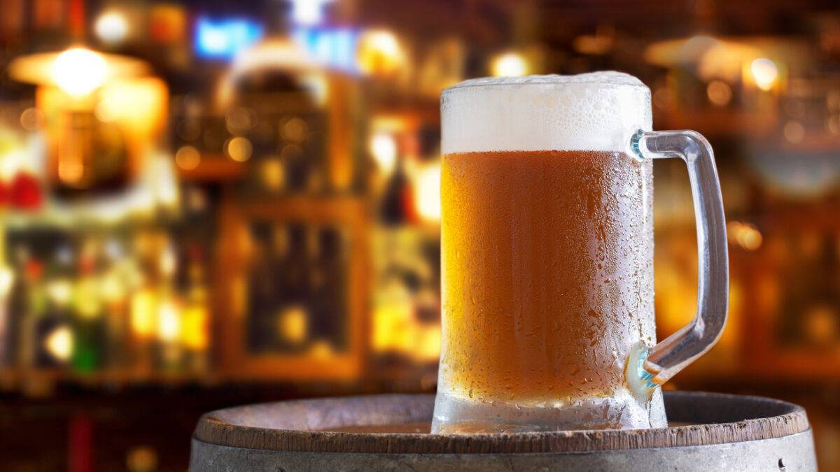 Cold mug of beer in a bar on wooden barrel