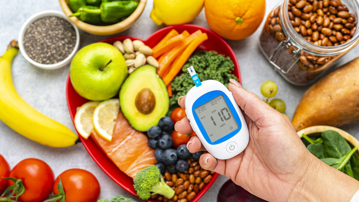 Hand holding glucometer on healthy food background. High resolution 42Mp studio digital capture taken with SONY A7rII and Zeiss Batis 40mm F2.0 CF lens