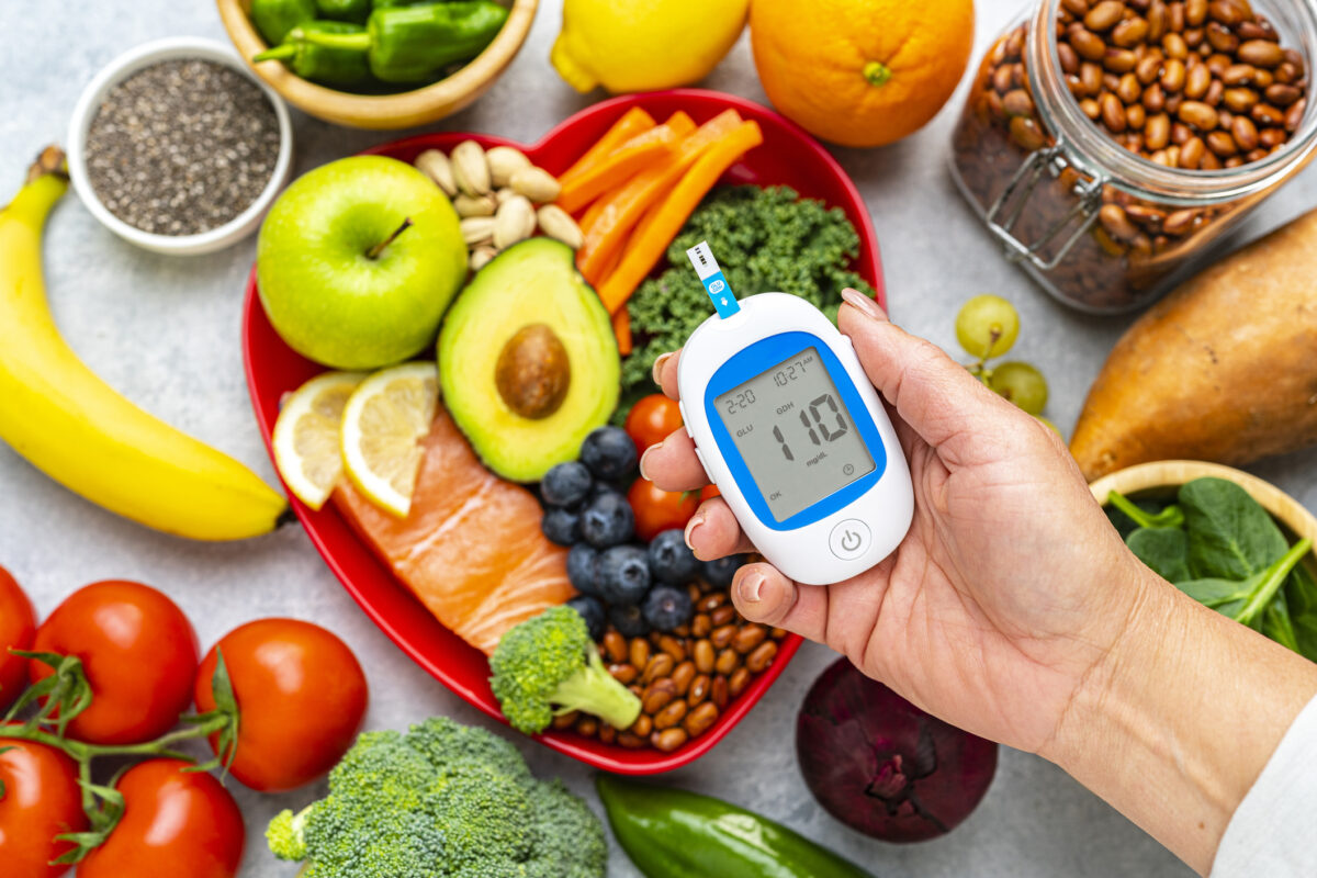 Hand holding glucometer on healthy food background. High resolution 42Mp studio digital capture taken with SONY A7rII and Zeiss Batis 40mm F2.0 CF lens