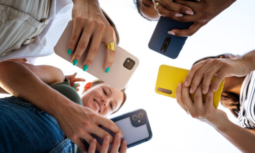 Low angle view of four female friends using phone in a circle. Focus on phones and hands. Lifestyle and technology.