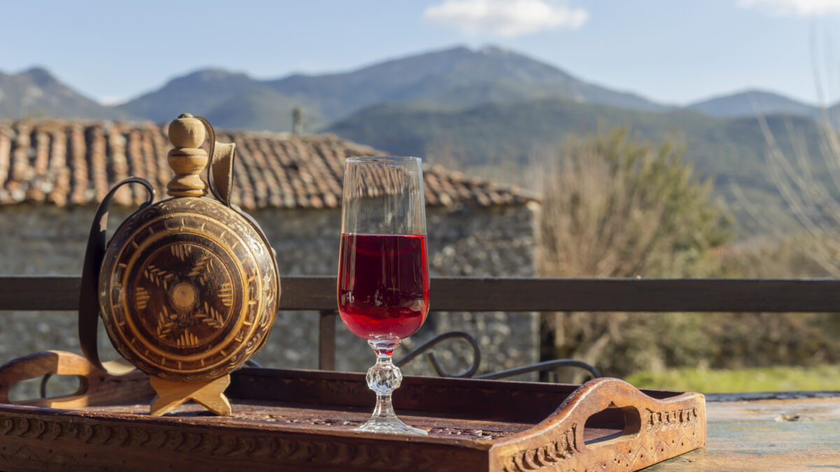 Rural still life. Red wine in a flask and a glass close-up on a wooden table against the backdrop of the mountains in winter