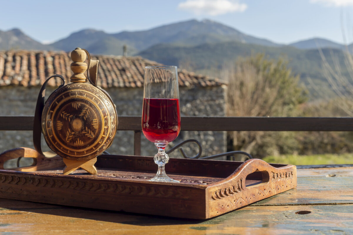 Rural still life. Red wine in a flask and a glass close-up on a wooden table against the backdrop of the mountains in winter