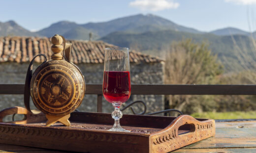 Rural still life. Red wine in a flask and a glass close-up on a wooden table against the backdrop of the mountains in winter