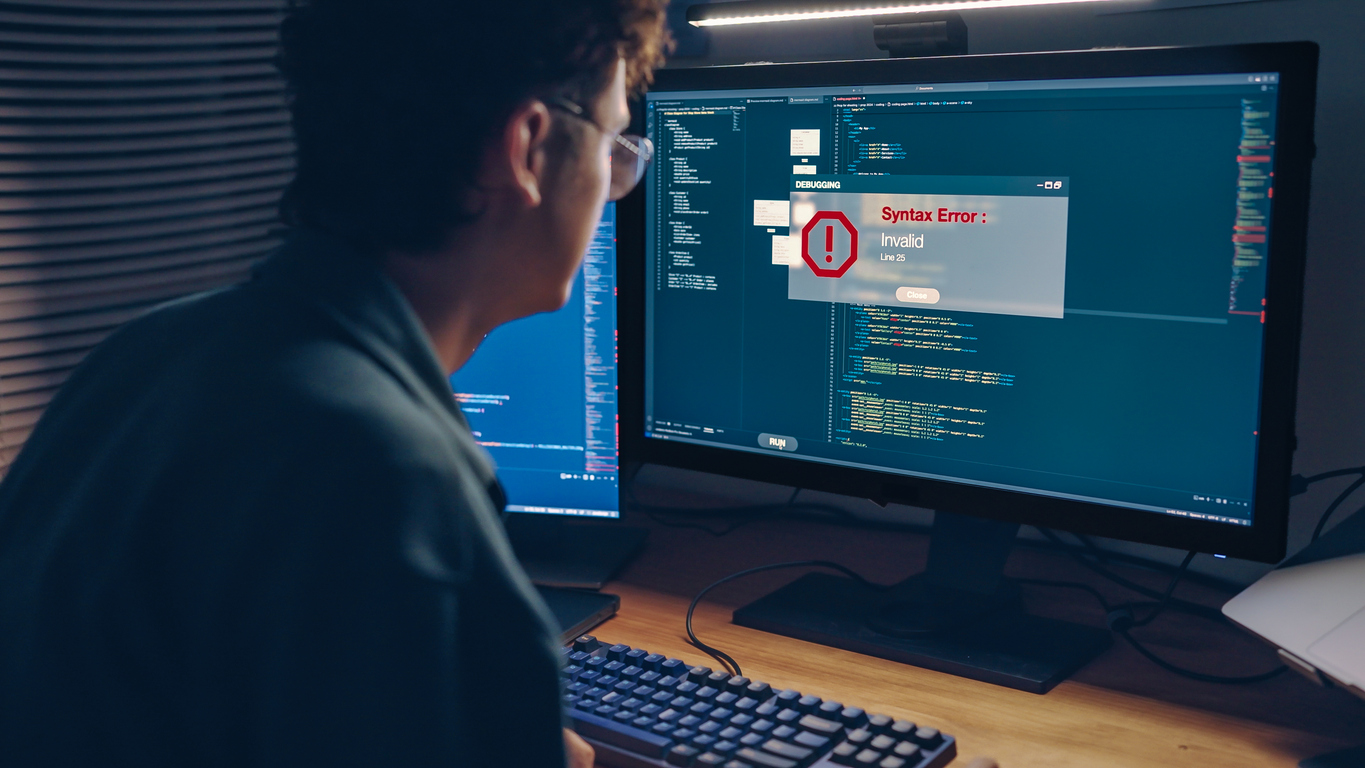 Tired white man programmer or IT specialist software developer works on debugging code warning Error System failure when the code contains a violation of the programming language's rules solving during code validation