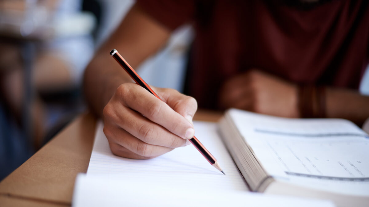 Closeup shot of a young man writing on a note pad