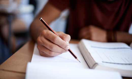 Closeup shot of a young man writing on a note pad