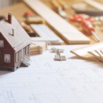 Construction and home renovation concept, model house, work tools, house keys and draft project on a desktop