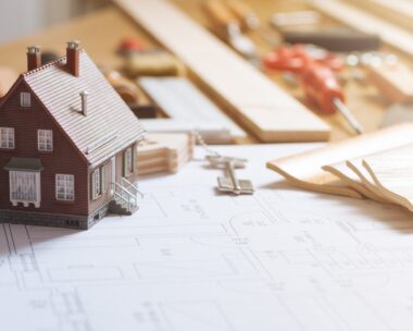 Construction and home renovation concept, model house, work tools, house keys and draft project on a desktop
