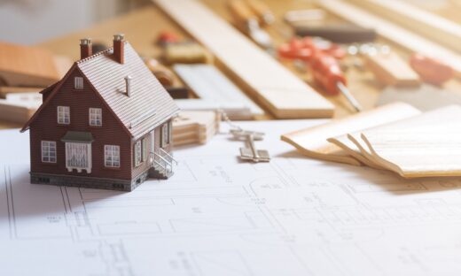 Construction and home renovation concept, model house, work tools, house keys and draft project on a desktop