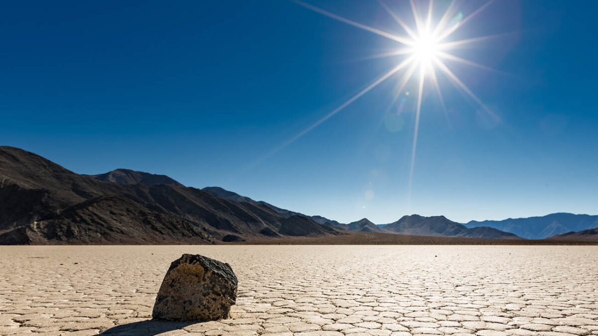 A lone "sailing rock" sits basking in the bright unrelenting sun at Racetrack Playa in Death Valley National Park, California