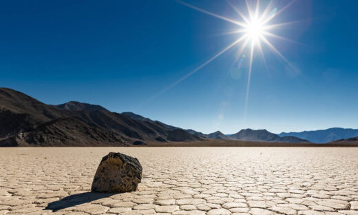 A lone "sailing rock" sits basking in the bright unrelenting sun at Racetrack Playa in Death Valley National Park, California