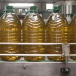 Bottling plant, row of large plastic bottles filled with olive oil.