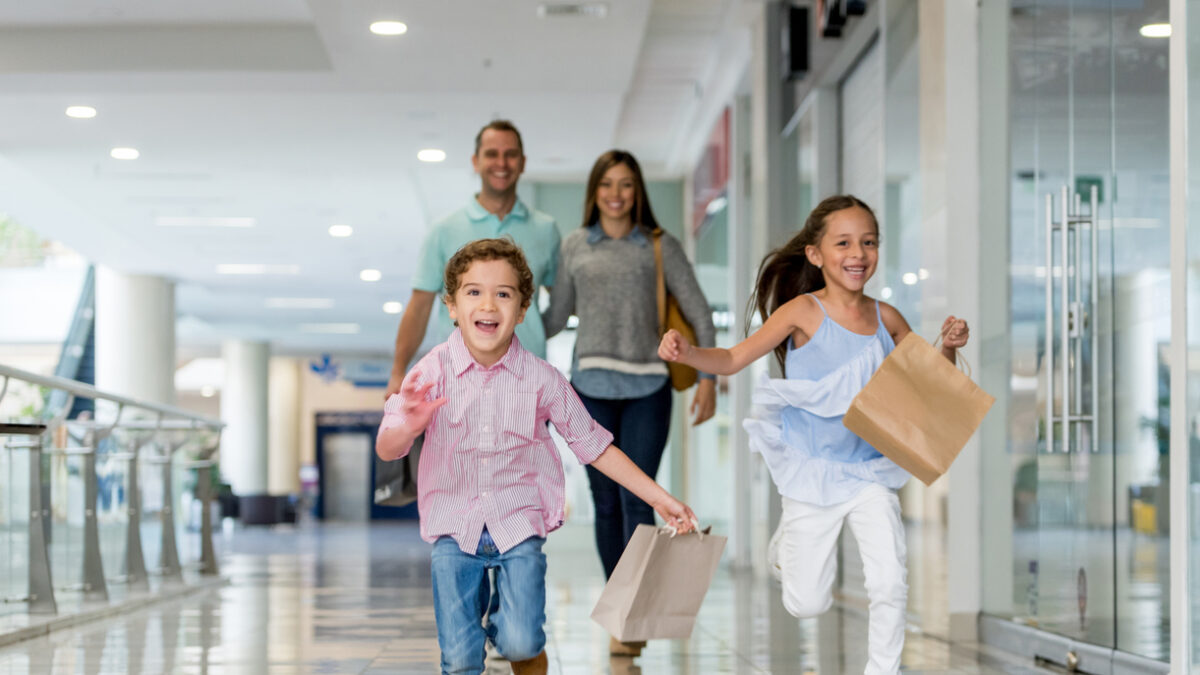 Happy Latin American family shopping and running towards the camera at the mall - lifestyle concepts