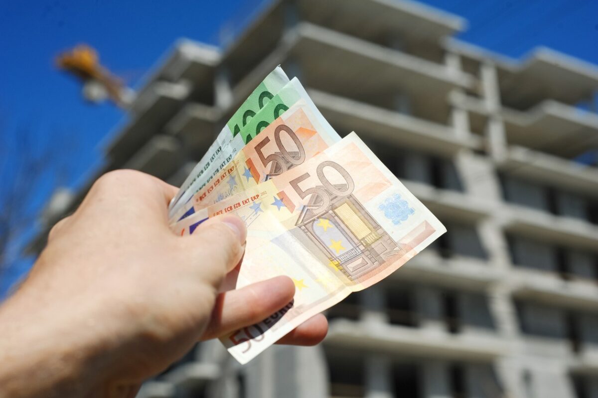 Man holding euro money in front of block building in build process