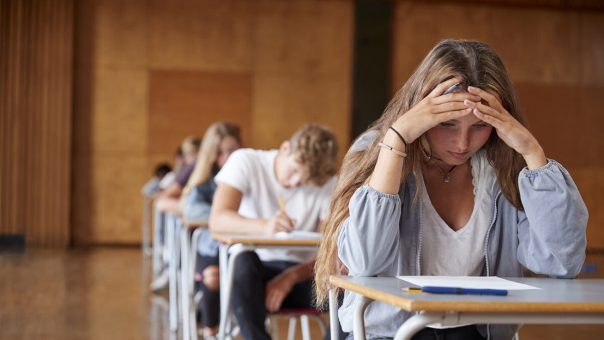 Anxious Teenage Student Sitting Examination In School Hall