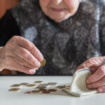Elderly woman sitting at the table counting money in her wallet