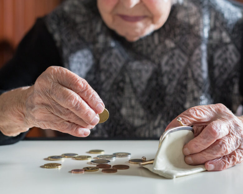 Elderly woman sitting at the table counting money in her wallet