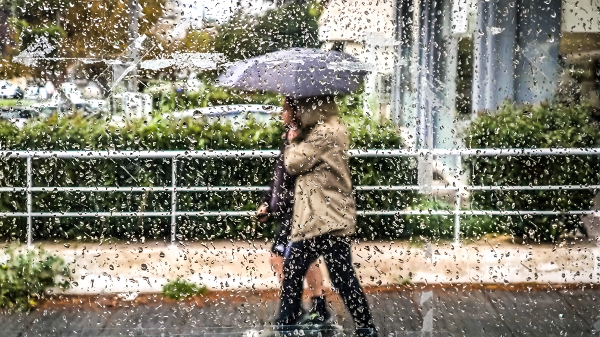 Άνθρωποι περπατούν με ομπρέλες στη βροχή