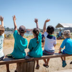 Students holding their hands up to volunter or ask questions of their teacher