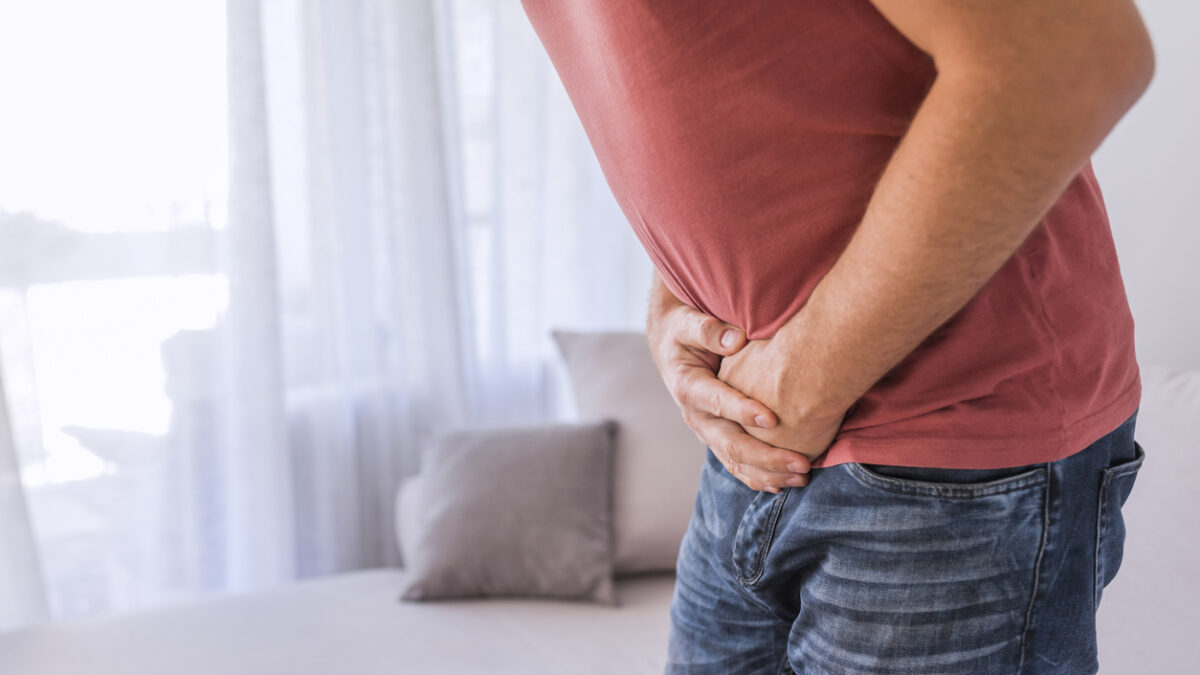 Photo of Unrecognizable Man covering his painful crotch. Mature man with urological problems suffering from pain at home during the day.