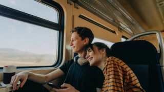 Photo of a smiling young couple travelling together by train
