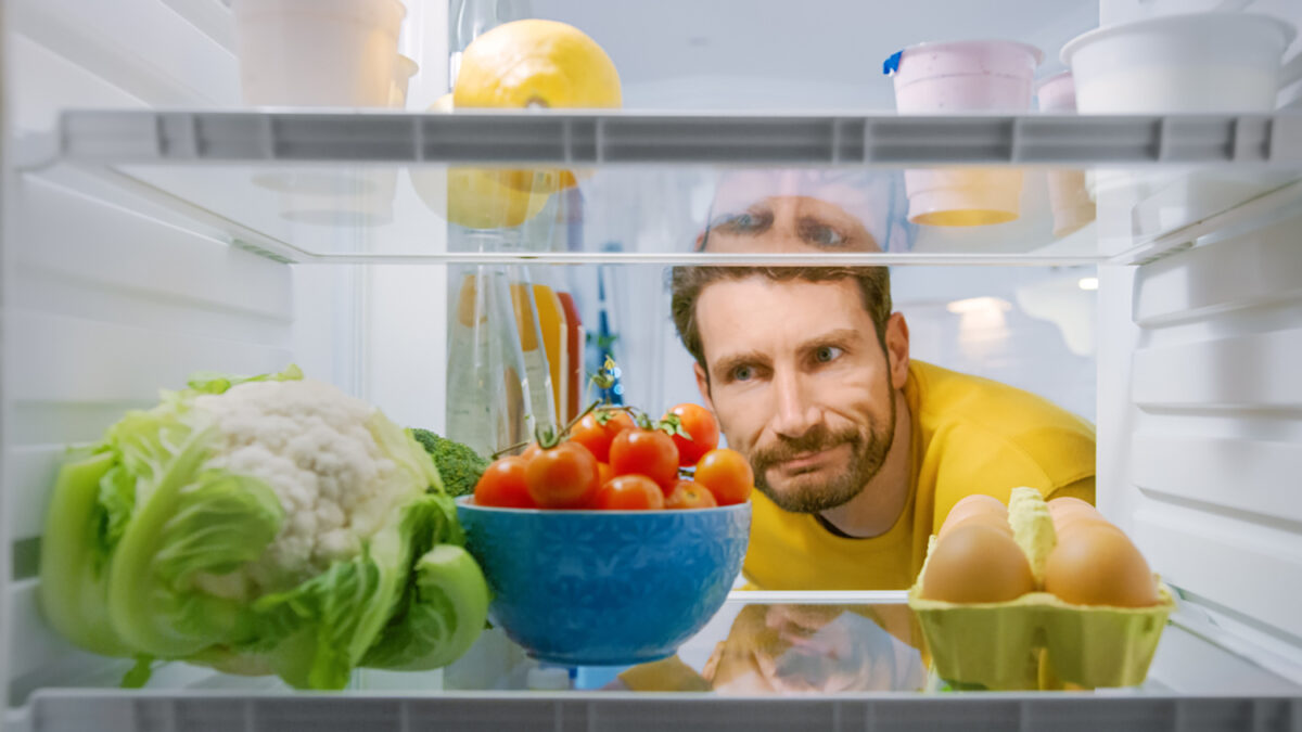 Inside Kitchen Fridge: Young Disappointed Man Looks inside the Fridge. Man Found Nothing for His Snack Time. Point of View POV Shot from Refrigerator full of Healthy Food
