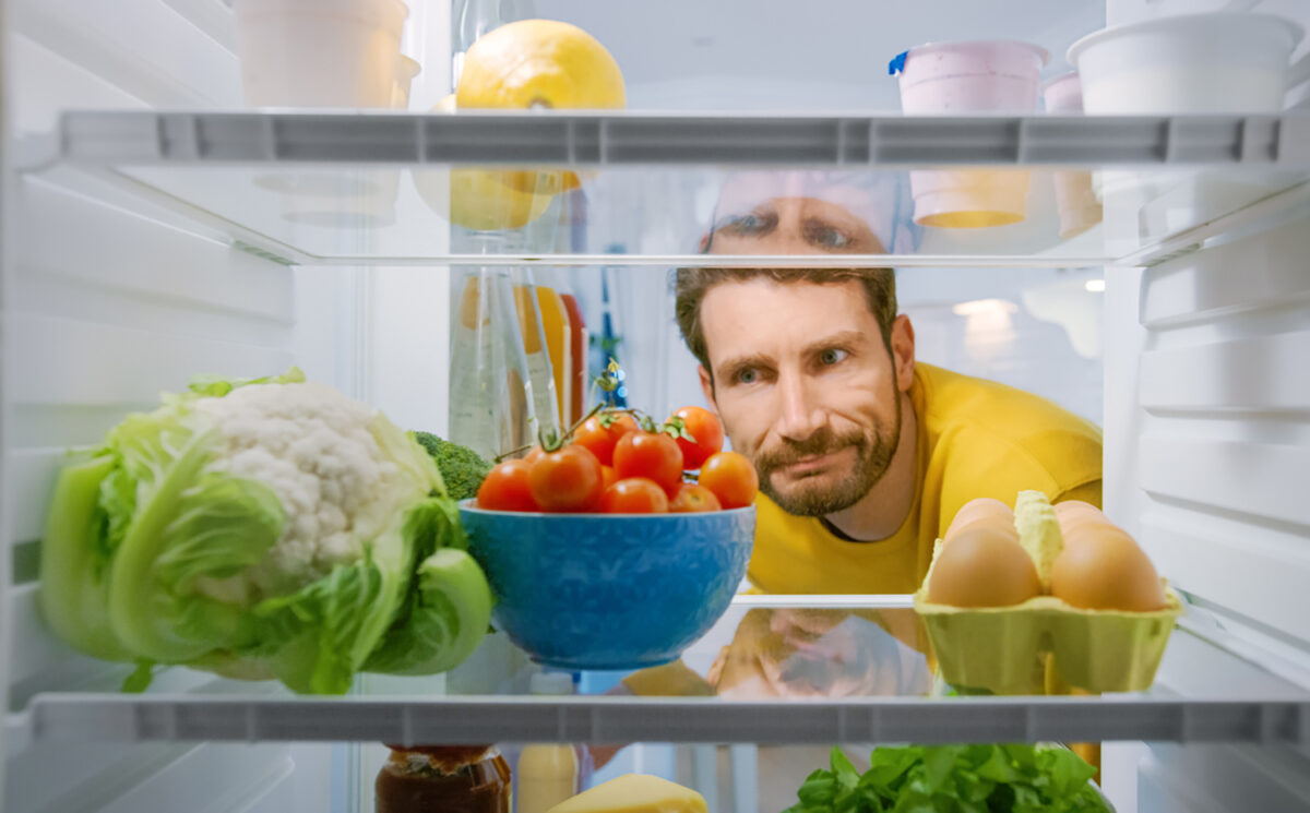 Inside Kitchen Fridge: Young Disappointed Man Looks inside the Fridge. Man Found Nothing for His Snack Time. Point of View POV Shot from Refrigerator full of Healthy Food
