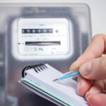 Woman with pen and notepad writes the electricity meter readings. Payment of utility services.