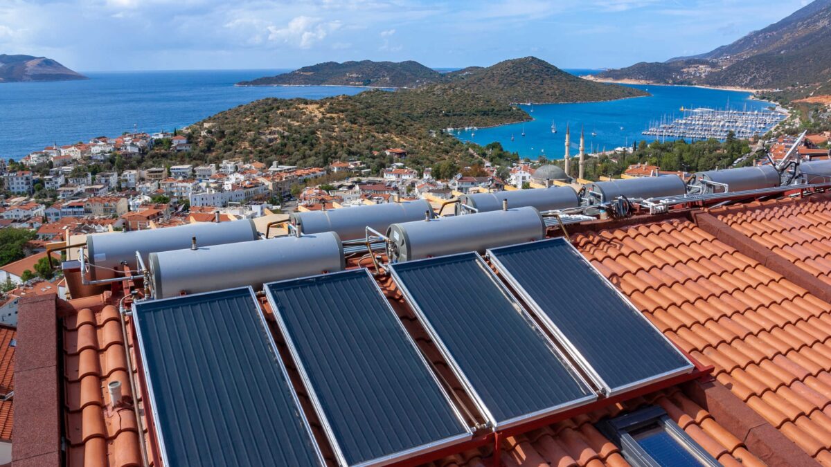 Solar water heater installed on tile roof of house for economical heating of water. A lot of large water tanks