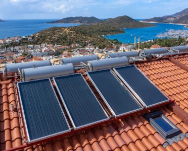 Solar water heater installed on tile roof of house for economical heating of water. A lot of large water tanks